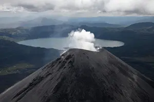 Smoking: Bird's eye view of smoking Karymsky volcano, behind