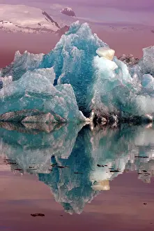 Rising: Blue iceberg reflected in the water, mountains rising