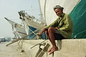 Boatman: Boatman - sitting on wall - with Phinisi boats behind him