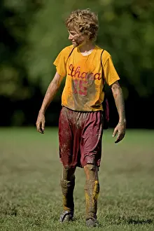 Football: Boy Age 12 Playing Soccer covered with mud