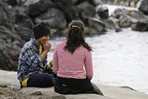 Rapa: A boy and girl sitting by the sea eating 'curantoI