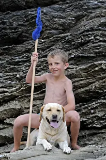 Pieces: Boy and his Labrador dog on the rocks Britain France