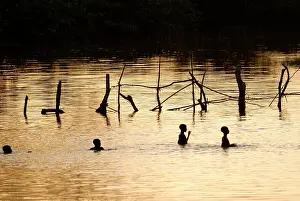 Riverine: Boys playing in a river at sunset