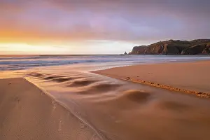 Flows: A brook flows over the sandy beach into the sea