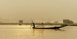 Fishermen: Burmese Fisherman fishing at dawn with village in