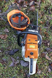 Helmets: Chainsaw and helmet resting on the ground in winter