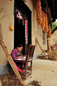 Qinling: Child - doing homework outside farmer's house -