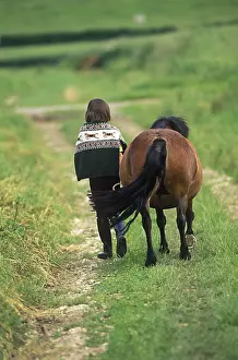 Promenade: Child walking with her pony on a path