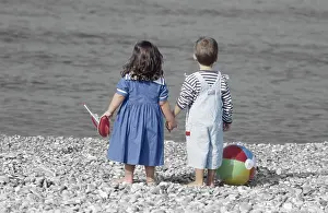 Mono: Children - boy & girl holding hands on beach, with