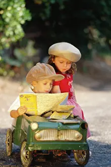 Reading: CHILDREN - cute boy and girl in toy car, reading map