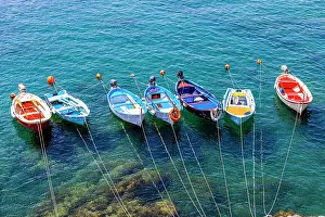 Attached: Colourful fishing boats attached to the rock lie
