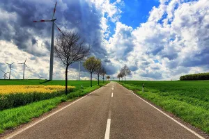 Economy: Country road, wind turbine, rape field in spring