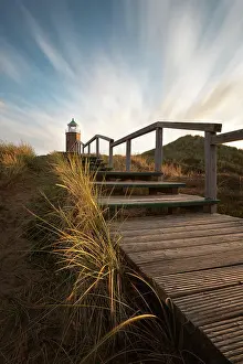 Boarded: Cross light, lighthouse with sand dune in the evening