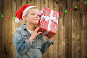 Present: Curious young boy wearing santa hat holding christmas
