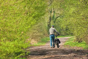 Cycling: Cyclist walking on dirt road in spring