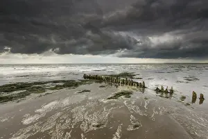 Oever: Dark clouds above the waddensea at low tide with a line of b