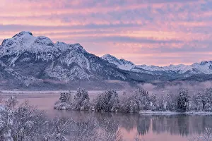 Alpine Upland: Dawn and sunrise at the wintry Forggensee in a snow-covered winter landscape in the foothills of the Alps