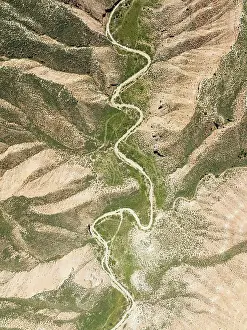 Gravel: Dirt road in the Gorafe Desert with green surroundings