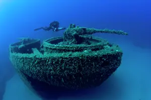Scooter: Diver exploring with scooter the bow with machine gun of the