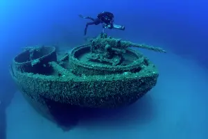 Scooter: Diver exploring with scooter the bow with machine gun of the