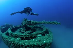Motor: Diver exploring with scooter the bow with machine gun of the