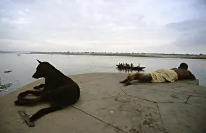 Ships: Dog and man lying beside the Ganges Varanaci India