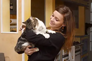 Arms: Domestic cat in the arms of his mistress smiling