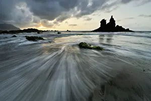 Flood: Dramatic cloudy atmosphere with rock formation at rising tide at sunset on the beach of Playa de Benijo