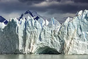 Glaciers: Dramatic glacier with threatening clouds and mountains in the background