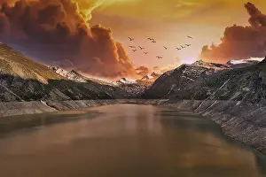 Moody: Dramatic sunset over a mountain lake with flying birds and clouds