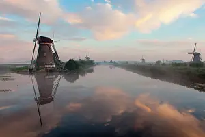 Windmill: Dutch windmill in beautiful morning light with reflection in the water in Kinderdijk