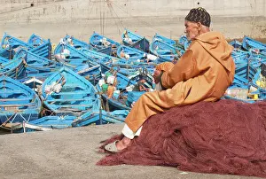 Attractive: Elderly man resting on heap of fishing nets and