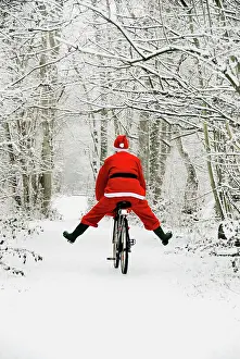 Bikes: Father Christmas - riding bicycle in snowy woodland path