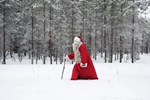 Claus: Father Christmas / Santa waking through snow landscape w