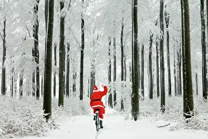 Cycling: Father Christmas waving and cycling through woodland