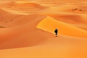 Chebbi: Female hiker in the desert Erg Chebbi at sunset