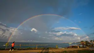 Exercising: Female jogger runs past 180 degree rainbow after