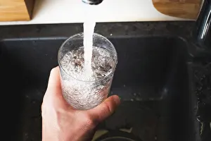 Style: Filling glass of water from stainless steel kitchen
