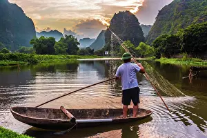 Pole: Fisherman on boat in Trang An, a scenic area near