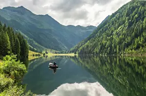 Fisherman: Fisherman on Lake Riesachsee with reflection of