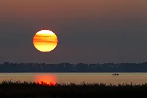 Rowing: Fishermen in rowing-boat on lake at sunset, Western