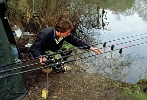 Anglers: Fishing - carp angler by rods on rets checking alarms