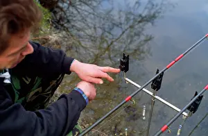 Anthony Harrison: Fishing - carp angler by rods on rets checking alarms