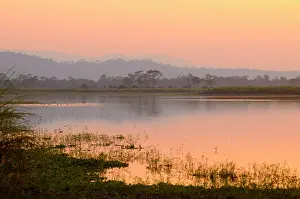 Surrounded: Freshwater lake surrounded by forested hills during sunset