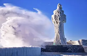 Heavy: Frozen lighthouse and pier on stormy winter day