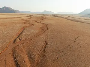Eroded: Gemsbok (Oryx gazella). Roaming an arid plain with dried-up river beds and isolated mountain ridges in the distance