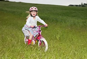 Cycling: Girl enjoying cycling fast on farm field