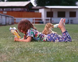 Jack: Girl feeds young lions and reads a book, England