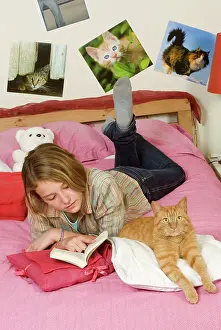 Reading: Girl lying on bed reading - with ginger cat lying