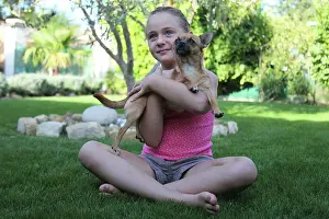 Sized: Girl sitting in the grass with a Chihuahua - France